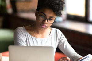 A young female adult studying with an open laptop